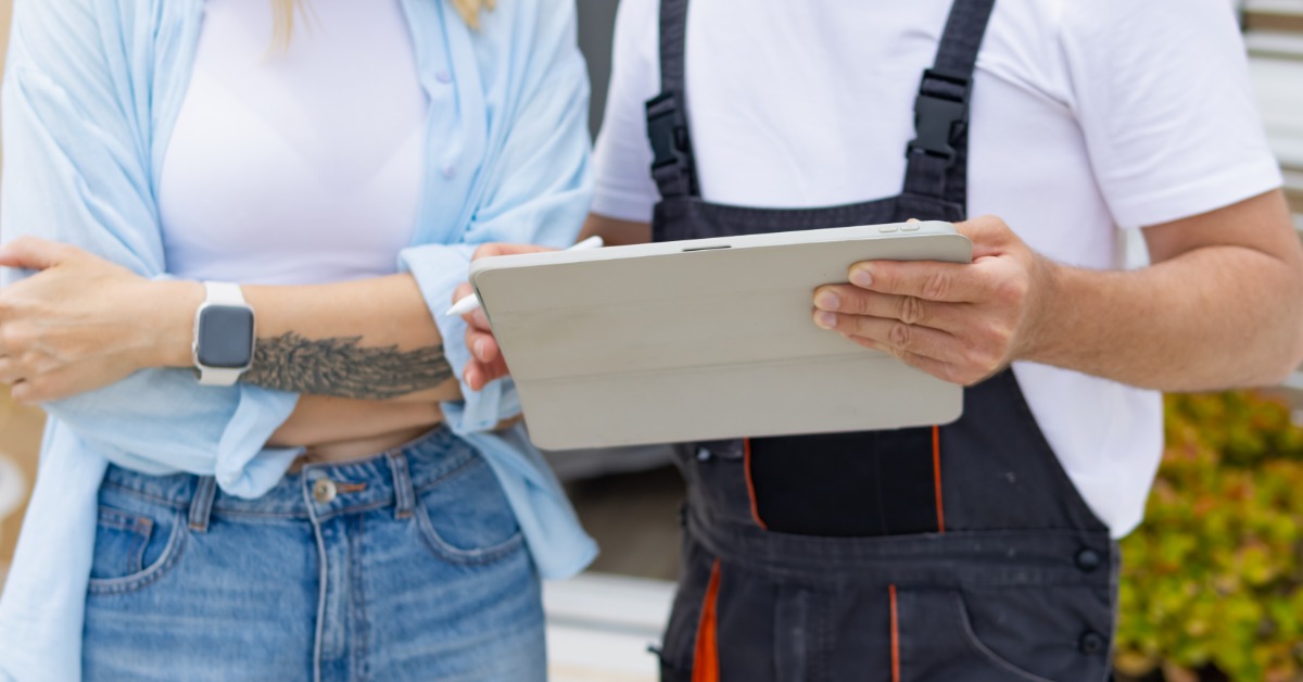 A contractor reviews project details on a tablet with a client during an on-site building consultation.