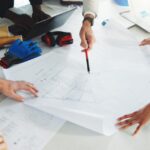 Contractors review construction plans together while discussing details for an upcoming building project.