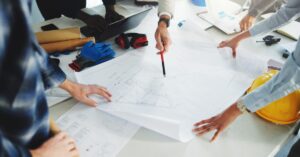Contractors review construction plans together while discussing details for an upcoming building project.