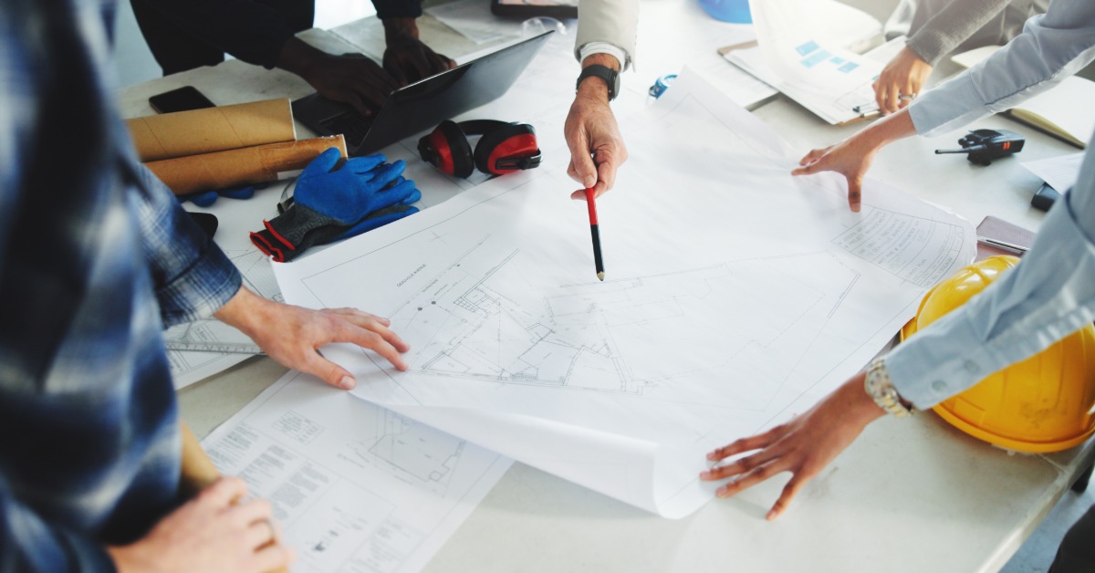 Contractors review construction plans together while discussing details for an upcoming building project.
